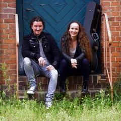 Kevin Sauer und Anja Sauer (Duo Inuso) sitzen auf einer Treppe vor einem Backsteingebäude