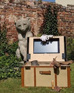 Museumskoffer im Museumsgarten mit Bärenskulptur