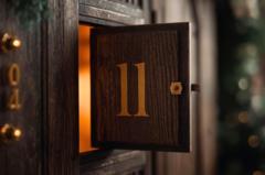 Ein Adventskalendertürchen mit einer 11 darauf, bestehend aus Holz in schummrigem roten Licht.