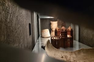 In einem Regal steht das Modell der Marienkirche, im Hintergrund die Büste aus Backstein einer Frau mit Krone, vorne ein graues Objekt.