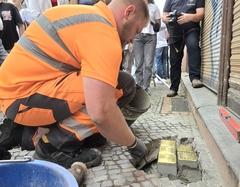 Ein Mitarbeiter in oranger Arbeitskleidung verlegt die Steine